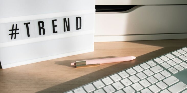 Keyboard and pink pen next to a sign that says #TREND Photo by Walls.io on Unsplash