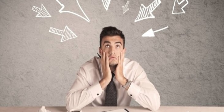 Arrows pointing to a man sitting in office with a coffee and book at his desk