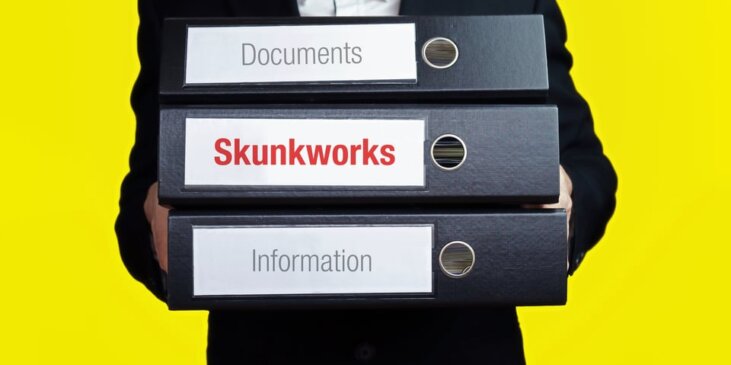 Person carrying binders labeld Documents, Information, Skunkworks