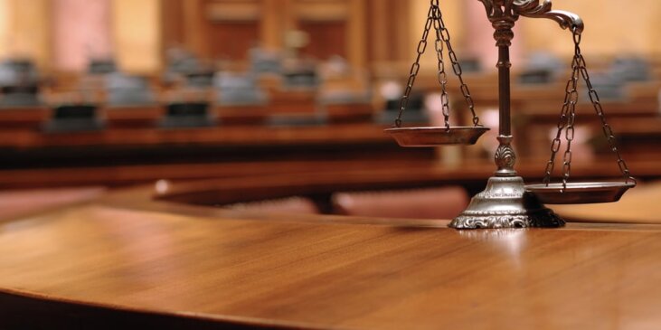 Blurry courtroom with the scales of justice in the foreground