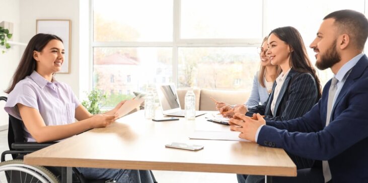 Wheelchair using woman being interviewed by a panel of business people